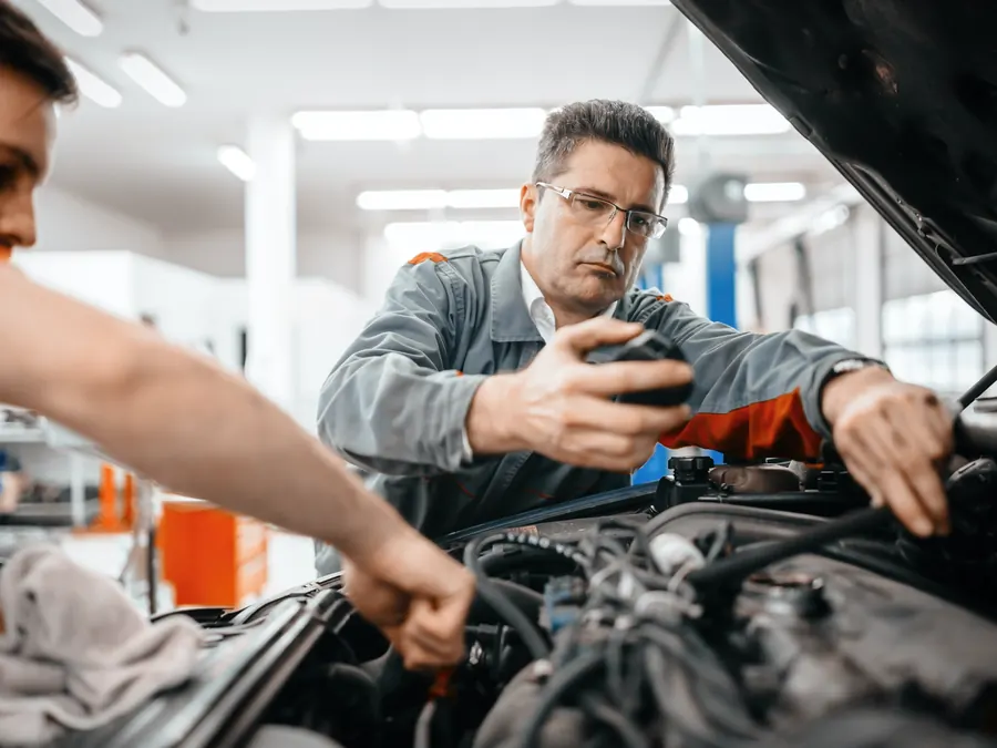 Dos mecánicos revisando juntos el motor de un vehículo